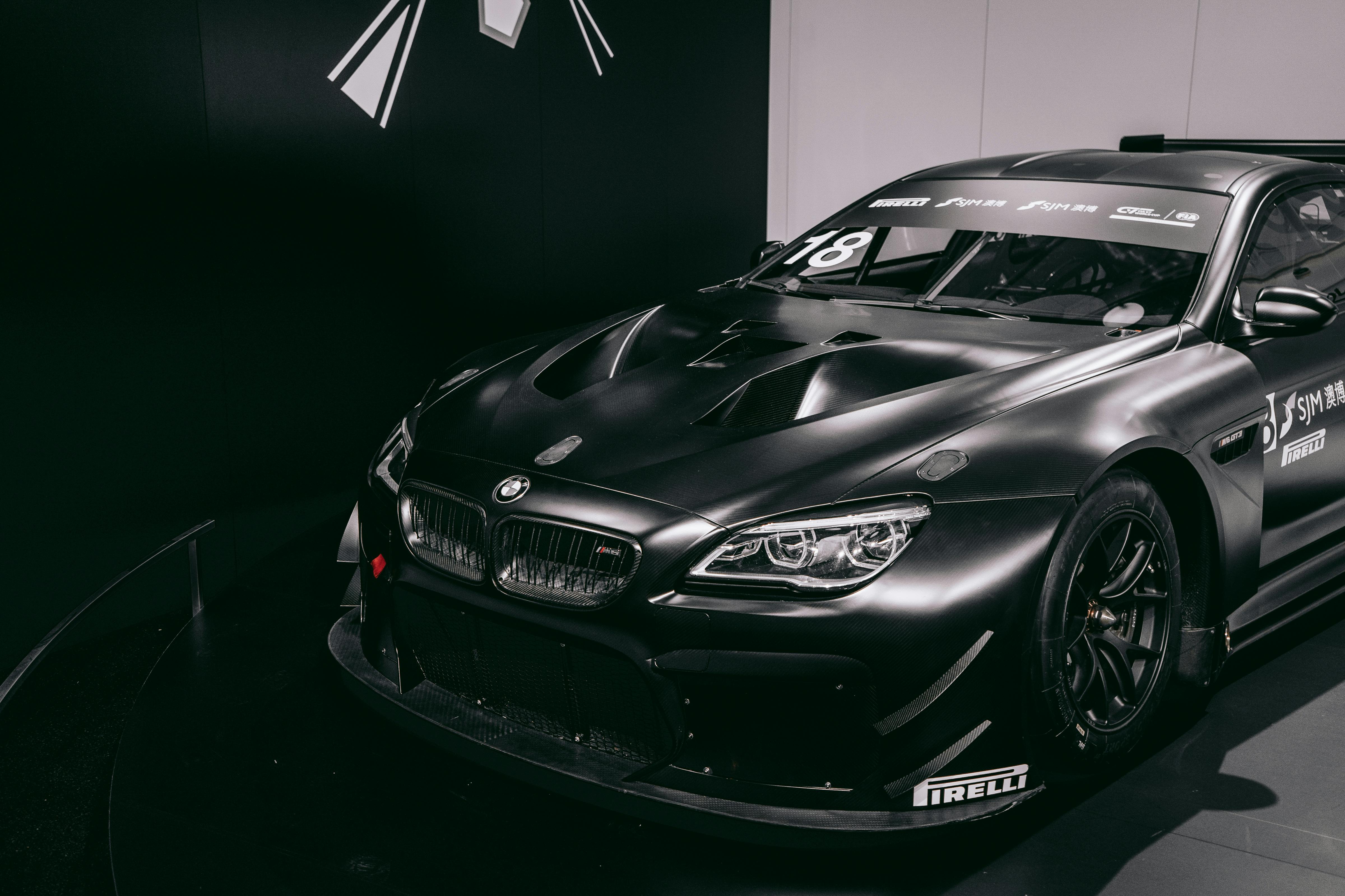 Black BMW racing car displayed in a Munich exhibition, showcasing modern automotive design.